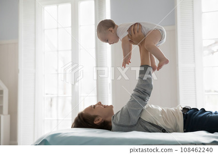 Loving mother lying on comfortable bed play with infant 108462240