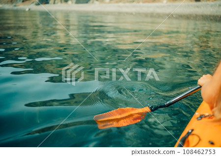Kayak paddle sea vacation. Person paddles with orange paddle oar on kayak in sea. Leisure active lifestyle recreation activity rest tourism travel 108462753