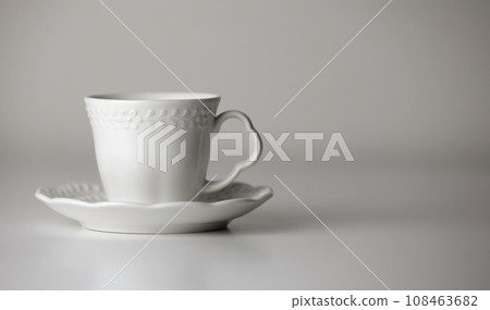 White tea cup and saucer with a pattern for drink on white background. Ceramic coffee cup or mug close up. Mockup classic porcelain utensils. copy space 108463682