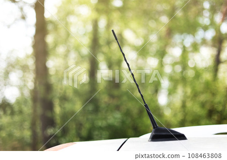 green forest behind car antenna.Car antenna for receive the radio waves on roof car. Selective focus and close up 108463808