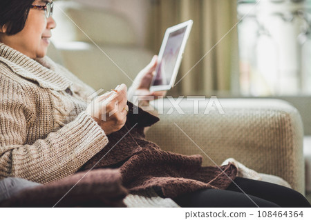 Asian old woman knitting crochet with taplet at home 108464364