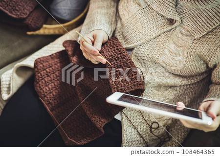 Asian old woman knitting crochet with taplet at home 108464365