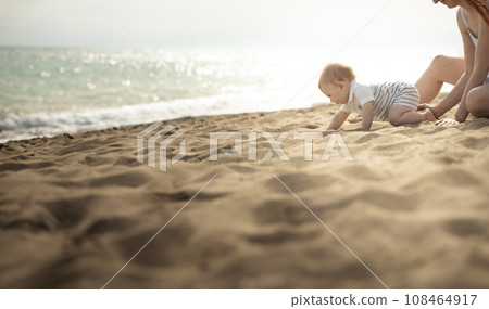 A little baby boy crawling on a sand on the seaside A little baby boy crawling on a sand on the seaside 108464917