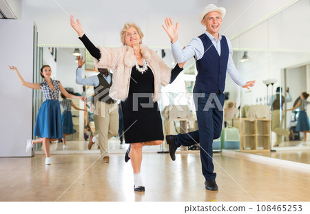 Man and elderly woman performing jazz dance in dancing room Man and elderly woman performing jazz dance in dancing room 108465253
