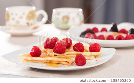 Breakfast of pancakes with fresh raspberries on table Breakfast of pancakes with fresh raspberries on table 108465260