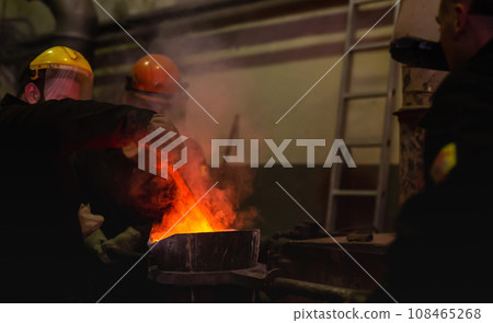 Pouring molten metal into a centrifugal machine in the foundry shop of metallurgical plant Pouring molten metal into a centrifugal machine in the foundry shop of metallurgical plant 108465268