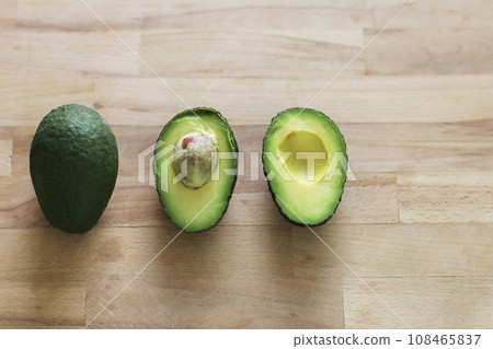 Isolated fresh organic avocados. Whole raw green avocado fruit, half with seed and a half without on wooden table. Design element for product label, catalog print, web use. Diet healthy concept 108465837