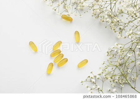 Cod liver oil omega 3 gel capsules isolated on white background. Fish oil gel capsules with a bouquet of spring flowers. Vitamins Cod liver oil omega 3 gel capsules isolated on white background. Fish oil gel capsules with a bouquet of spring flowers. Vitamins 108465868