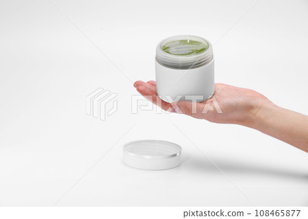 Woman's hand is holding a cosmetics jar with natural vegan green cream isolated on a white background with copy space for your design Woman's hand is holding a cosmetics jar with natural vegan green cream isolated on a white background with copy space for your design 108465877
