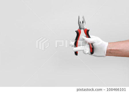 Man's hand in white glove raised holding a black and red tool 108466101