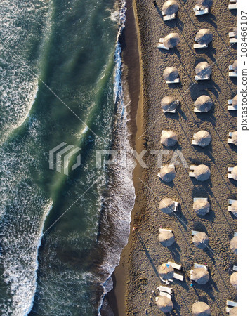 View from above, stunning aerial view of an amazing empty beach with white beach umbrellas and turquoise clear water with waves. 108466107