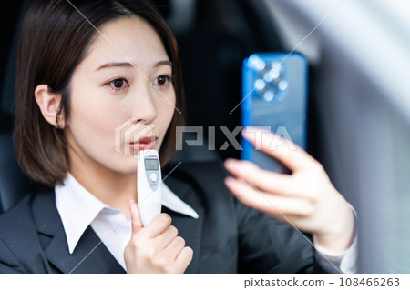 Young female driver recording her alcohol test results before a ride-sharing job 108466263