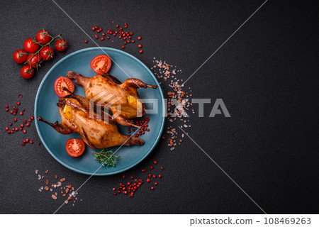 Roasted quail, partridge or pigeon stuffed with orange with spices and herbs 108469263