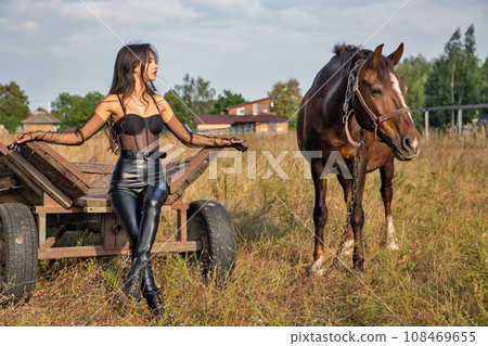 Beautiful young caucasian woman standing near the horse. 108469655