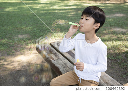 Boy making soap bubbles in the park 108469892