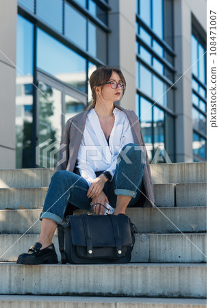 Successful beautiful business woman in suit with document walking to the meeting near modern office building. Successful beautiful business woman in suit with document walking to the meeting near modern office building. 108471007