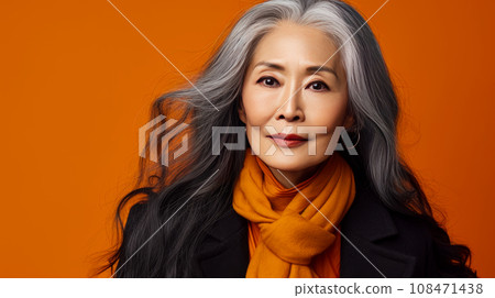 Smiling, elderly, gorgeous Asian woman with gray long hair and perfect skin, on an orange banner. 108471438