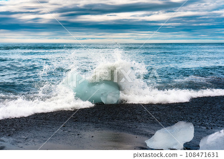 Wave crashing with iceberg on black sand beach in Diamond beach during summer at Iceland Wave crashing with iceberg on black sand beach in Diamond beach during summer at Iceland 108471631