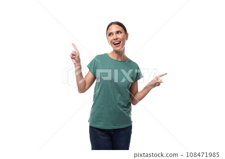 young beautiful brunette woman dressed in a green t-shirt points with her hand at copy space on a young beautiful brunette woman dressed in a green t-shirt points with her hand at copy space on a 108471985