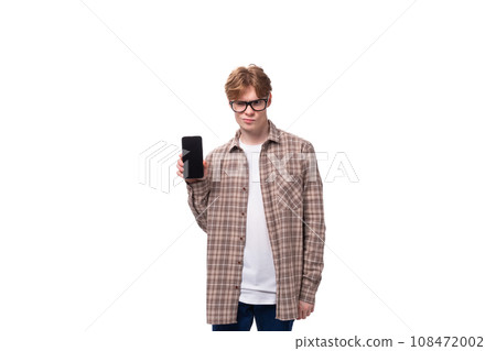 young stylish man with red hair dressed in a summer shirt shows a phone with a mockup 108472002