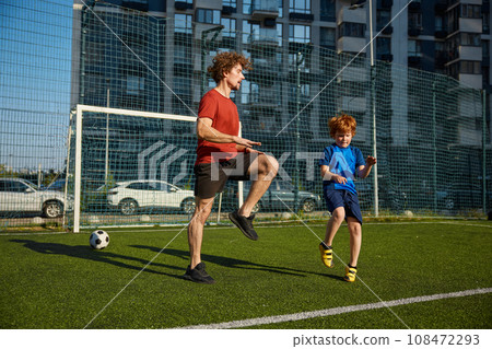 Dad and son doing physical workout and warming legs up before football game Dad and son doing physical workout and warming legs up before football game 108472293