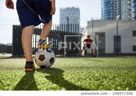 Father and son playing soccer, practicing shots on goal at stadium Father and son playing soccer, practicing shots on goal at stadium 108472308