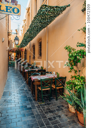Tables and chairs in the narrow streets of the old town of Rethymno. Tables and chairs in the narrow streets of the old town of Rethymno. 108472309