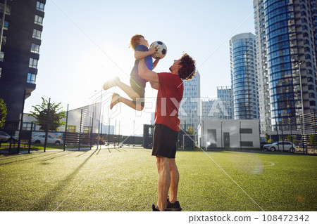 Happy father throwing excited son child in air after training football 108472342