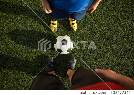 Father and son child playing football, focus on feet of soccer players Father and son child playing football, focus on feet of soccer players 108472345