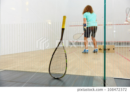 Squash racket leaned on net and sportspeople playing 108472372
