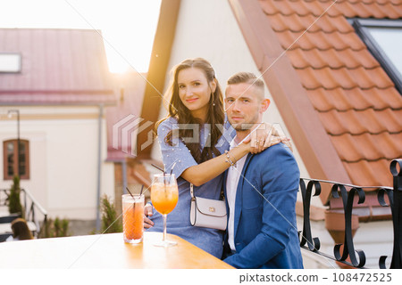 Beautiful couple in love is sitting at a table in an outdoor cafe on a date Beautiful couple in love is sitting at a table in an outdoor cafe on a date 108472525