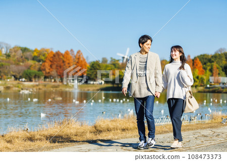 Young man and woman walking along the waterside 108473373