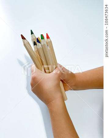Childs hand holds colored pencils. Learning and drawing concept 108473634