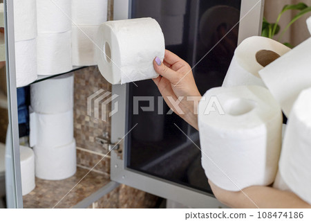 A woman is stocking up toilet paper at home A woman is stocking up toilet paper at home 108474186