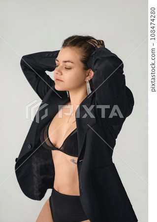 Portrait of a beautiful young woman with closed eyes in black lingerie sensually combing her hair into a bun Portrait of a beautiful young woman with closed eyes in black lingerie sensually combing her hair into a bun 108474280