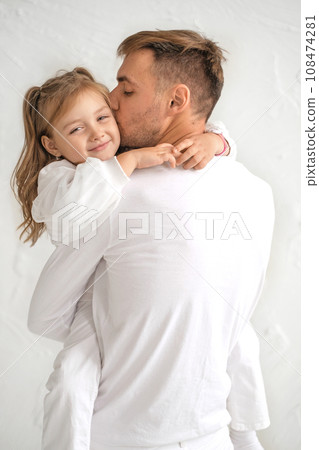 A loving Dad with his daughter in his arms kisses her gently on the cheek. World Father's Day A loving Dad with his daughter in his arms kisses her gently on the cheek. World Father's Day 108474281