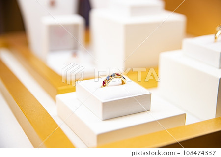 Gold ring with colorful gemstones presented on a white cushion Gold ring with colorful gemstones presented on a white cushion 108474337