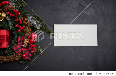 White envelope and Christmas wreath on a black background, top view White envelope and Christmas wreath on a black background, top view 108474396