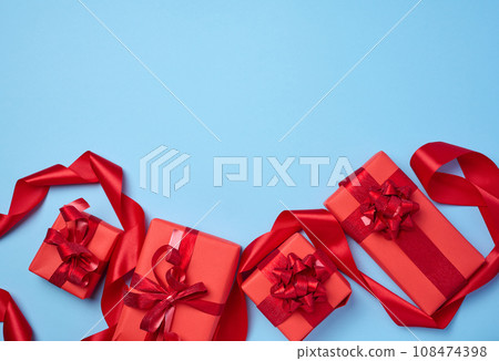 Boxes packed in red paper and tied with ribbon on a blue background Boxes packed in red paper and tied with ribbon on a blue background 108474398