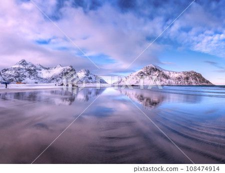Sandy beach with blue sea reflected in water and rocks in snow Sandy beach with blue sea reflected in water and rocks in snow 108474914