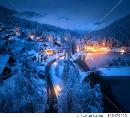 Aerial view of town in snow, road, forest, lake and houses 108474953