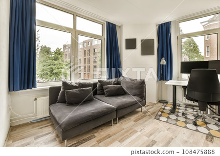 a living room with wood flooring and blue drapes hanging on the windows in the room is very spacious a living room with wood flooring and blue drapes hanging on the windows in the room is very spacious 108475888