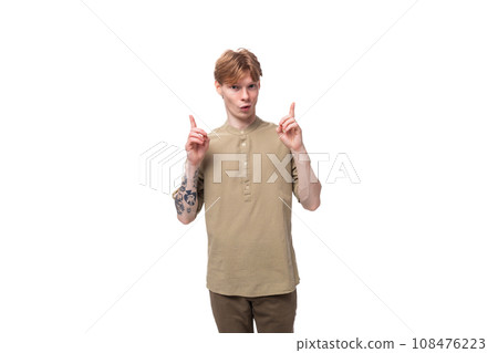young slender red-haired caucasian guy dressed in a khaki shirt with short sleeves tells the news 108476223