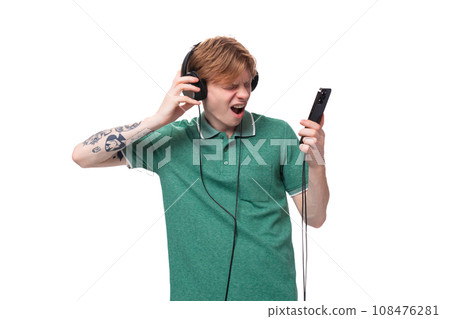 a young energetic bright red-haired caucasian guy in a green t-shirt dances to the music from the a young energetic bright red-haired caucasian guy in a green t-shirt dances to the music from the 108476281