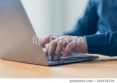 Man entrepreneur use laptop computer working at home. Male hands typing on the laptop keyboard. Business and technology concept of freelance work, work from home, businessman working at home office. 108476316