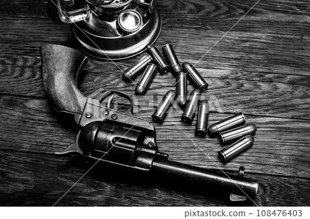 Revolver with cartridges on table with cold blast lantern 108476403