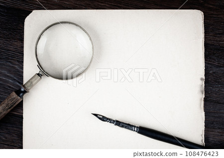 Magnifying glass with old paper and ink feather pen Magnifying glass with old paper and ink feather pen 108476423