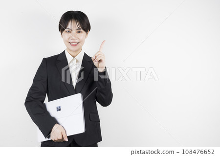 一名 20 多歲、身穿西裝的女性拿著筆記型電腦指著 108476652