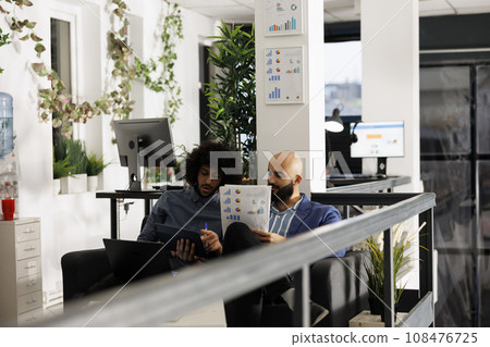 Arab entrepreneurs reviewing business strategies and analyzing papers with statistics charts. Company employees checking analytics report in corporate coworking space office Arab entrepreneurs reviewing business strategies and analyzing papers with statistics charts. Company employees checking analytics report in corporate coworking space office 108476725