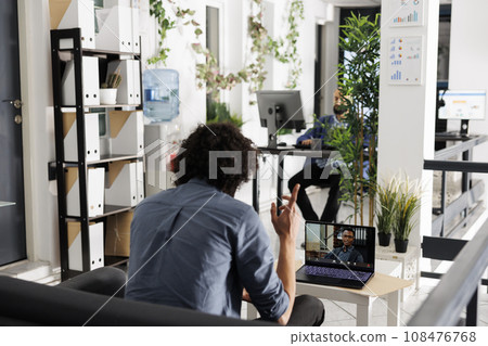 Business partners discussing start up project strategy in online meeting on laptop. Arab businessman in startup company working communicating with ceo remotely using videocall app Business partners discussing start up project strategy in online meeting on laptop. Arab businessman in startup company working communicating with ceo remotely using videocall app 108476768